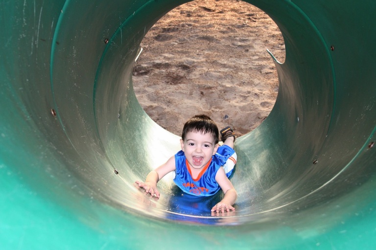 Boy Laughing And Playing With The Slide